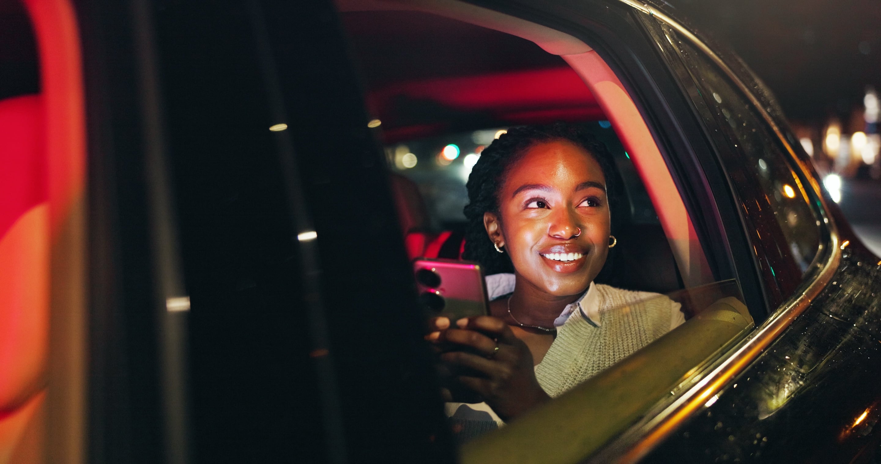 A passenger smiling from a car window at night
